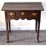 A George III oak lowboy, the rounded rectangular top above an arrangement of three drawers with