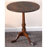 An early 19th century oak tripod tilt top occasional table with circular top, raised on turned