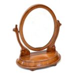 A Victorian mahogany swing toilet mirror with oval mirror plate on scroll supports,