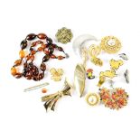 A quantity of costume brooches and an amber-coloured bead necklace.