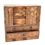 A Japanese parquetry inlaid trinket cabinet with tambour front enclosing three drawers with scene