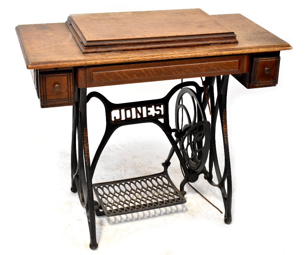 A Jones treadle sewing machine and table, oak top with hinged lid enclosing machine,