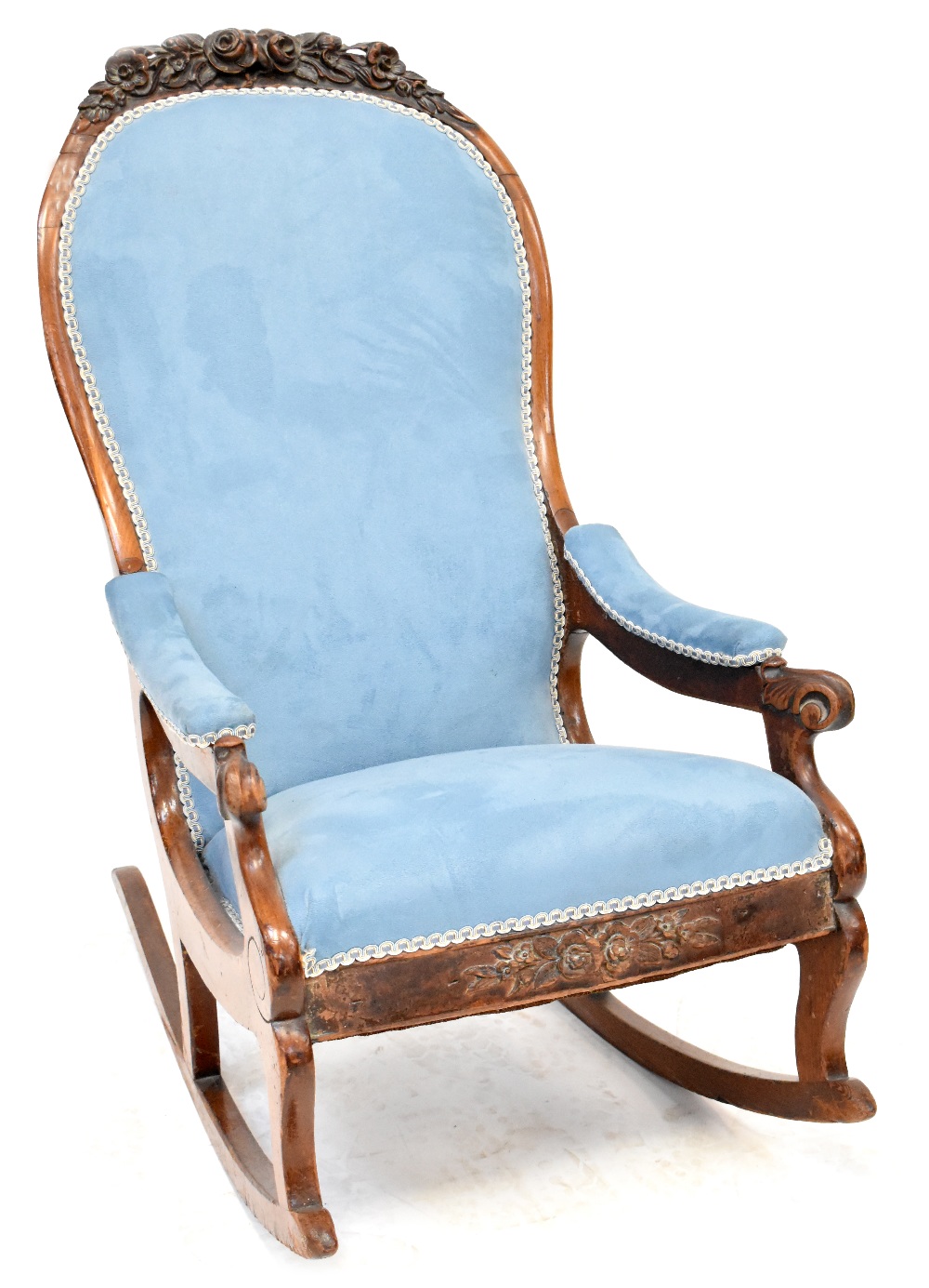 A Victorian walnut open arm rocking chair upholstered in a light blue velour with carved floral