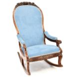 A Victorian walnut open arm rocking chair upholstered in a light blue velour with carved floral