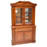 A modern break-front display cabinet with arched top above pair of glazed doors enclosing two