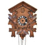 A Swiss wall-hanging cuckoo clock with carved leaf decoration, the dial set with Roman numerals,