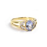 An 18ct yellow gold ladies' dress ring with oval facet cut blue stone and small diamonds to the