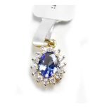 A 9ct yellow gold floral pendant with central oval blue stone and white stone surround.