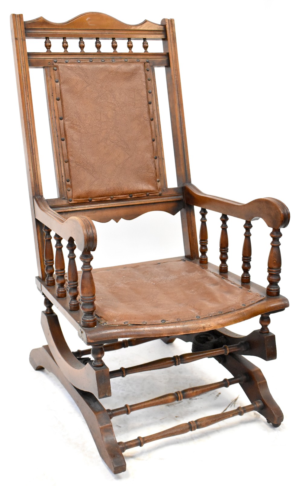 A late Victorian walnut American rocking chair, upholstered with studded leatherette.