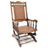 A late Victorian walnut American rocking chair, upholstered with studded leatherette.