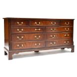 A Reprodux reproduction mahogany veneered crossbanded chest of drawers with central drawer flanked