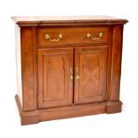 A modern side cabinet with central hinged section above a single drawer and pair of panelled doors