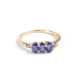 A 10ct yellow gold ladies' dress ring set with three oval blue stones and diamond chips to the