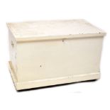 A large white painted pine blanket box with twin metal carry handles, on plinth base to castors,