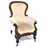 A Victorian mahogany spoon back armchair with carved scroll ends, upholstered in mushroom velour,