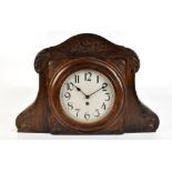 A large Arts & Crafts carved oak school clock, the arched canopy carved with initials and the date