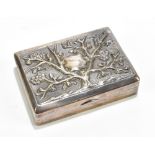 A white metal rectangular snuff box with repoussé floral decoration surrounding a vacant shield