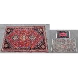 A large Middle Eastern hand knotted rug with stylised detail on predominantly red ground,