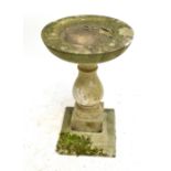 A small composite stone bird bath on baluster column to stepped square section base, diameter