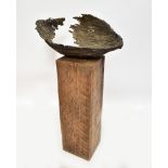An oval bronze sculpture of pierced and torn form mounted on a tall square wooden plinth, height