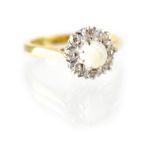 An 18ct gold ring with white opal within a border of tiny diamonds, size K, approx 3.6g.