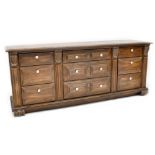 An oak-effect dresser base comprising nine fielded and panelled drawers with ceramic handles,