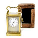 An early 20th century brass carriage clock, the circular dial set within an engine turned surround,