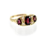 A vintage 9ct gold ring set with three graduated red stones separated by two rows of two small