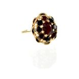 A yellow metal cluster ring set with central garnet in a surround of eight garnets,