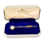 A 9ct yellow gold stick pin with single pearl in sunburst setting.