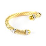 A 14ct yellow and white gold bangle of twisted rope form set with small white diamonds.