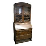 A c1930s oak bureau bookcase, the domed top above a pair of glazed doors,