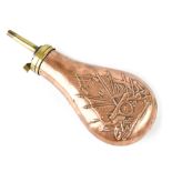 A brass mounted copper powder flask with embossed decoration depicting rifles, flags and cannon.
