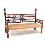 An Indonesian hardwood settee with bobbin turned supports and rush woven seat, on turned legs,