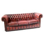 A modern Chesterfield three-seater sofa upholstered in oxblood studded leather, width 195cm.