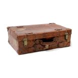 A vintage leather-bound leather suitcase with traces of shipping label to the top,