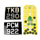 Two replica car number plates 'PCM 922' and TKB 209' and a yellow plastic wall hanging with the
