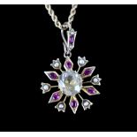 A yellow metal starburst pendant set with a central topaz in a surround of seed pearls and rubies,