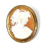 A yellow metal brooch set with shell cameo depicting a Classical lady with a wreath of grapes and