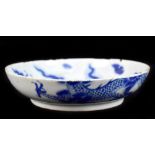 A Chinese blue and white shallow bowl decorated with a dragon amongst clouds, with painted Kangxi