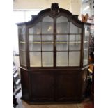 A large early 20th century German oak display cabinet with arched canopy above glazed doors with
