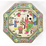 A Chinese Famille Rose charger of octagonal form decorated with figures beside a basket of fruit,