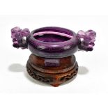 A Chinese amethyst coloured glass censer with twin pierced handles and raised on an associated