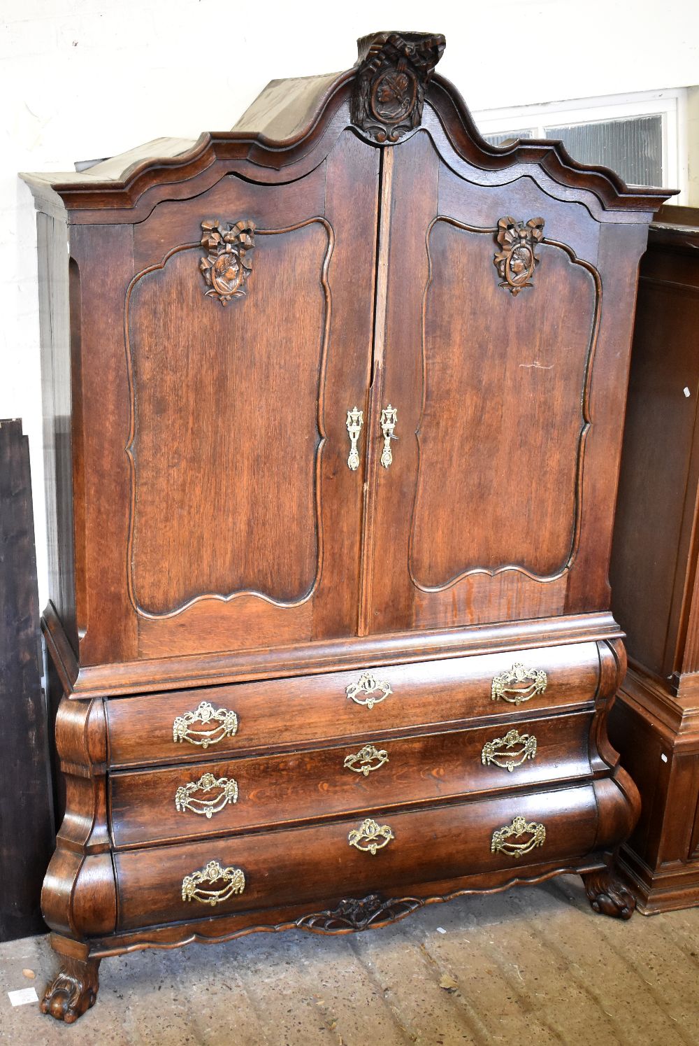 A large late 19th /early 20th century German oak armoire with carved shaped canopy above twin