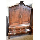 A large late 19th /early 20th century German oak armoire with carved shaped canopy above twin