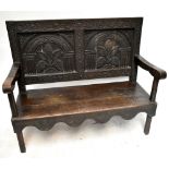 An 18th century oak settle with later carved decoration, panelled back and shaped apron, on stile