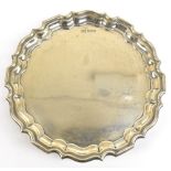 WALKER & HALL; a George V hallmarked silver waiter with cast scalloped edge raised on three