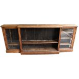 A Victorian oak breakfront bookcase with central section enclosing adjustable shelves, flanked by