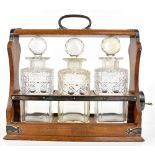 WALKER & HALL; an oak tantalus with silver plated mounts, housing three hob nail cut decanters,