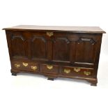 An 18th century oak coffer with panelled decoration to the front above three base drawers, raised on